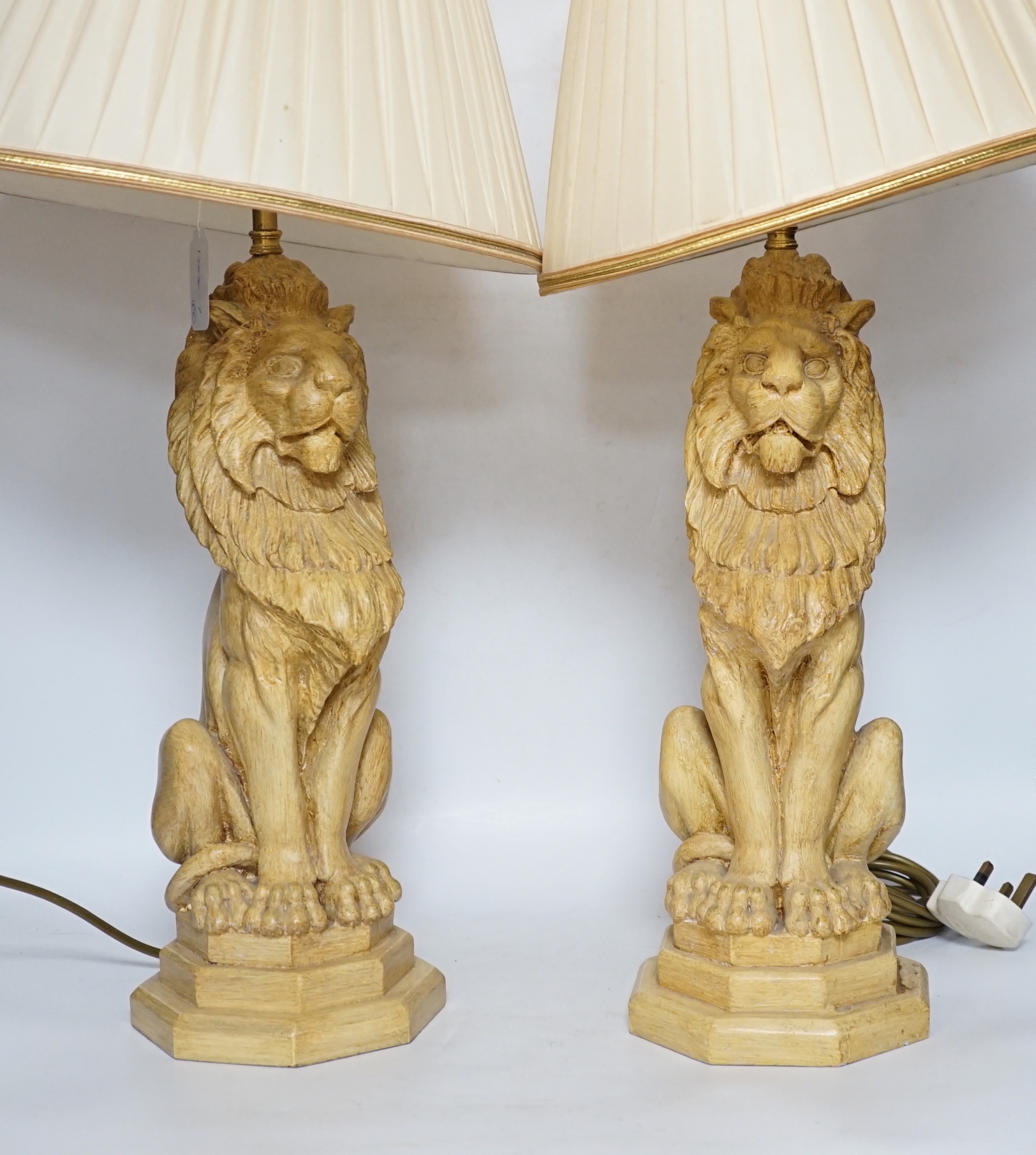 A pair of Thomas Blakemore composition lion lamps with cream shades, 64cm